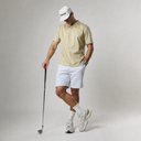 Man in golf attire holding a club on a plain background