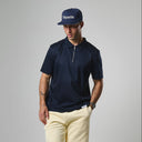 Man wearing a navy polo shirt and cap with 'Etiquette' branding on a gray background