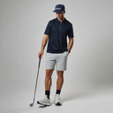Man in golf attire holding a club on a plain background
