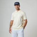 Man wearing a cream polo shirt and navy cap with 'Esquire' branding on a gray background