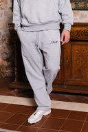 Person wearing a gray tracksuit with a brand logo in a rustic indoor setting